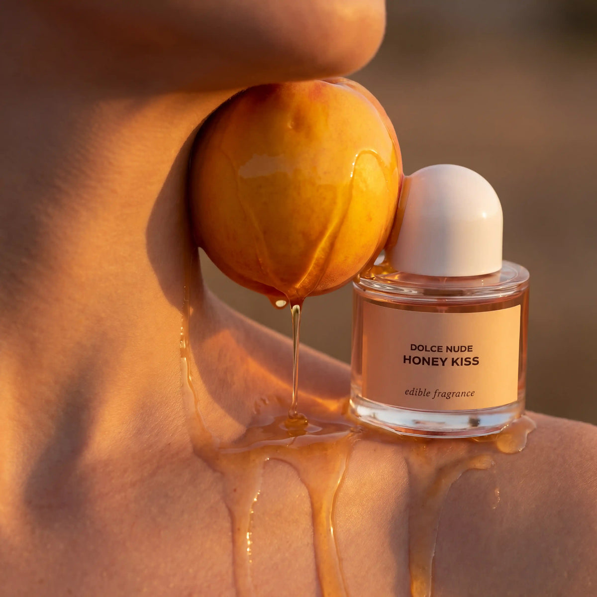 DOLCE NUDE Honey Kiss edible fragrance bottle with vibrant peach and luxurious golden liquid backdrop